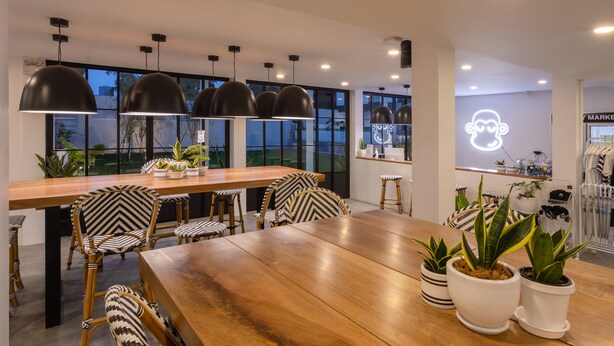 A modern dining area with a wooden table, black and white patterned chairs, potted plants, and pendant lighting. - Blu Monkey Hub & Hotel Ranong (Ranong)