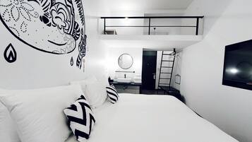 Un dormitorio moderno con una cama grande, un mural en la pared, un televisor y un pequeño balcón.