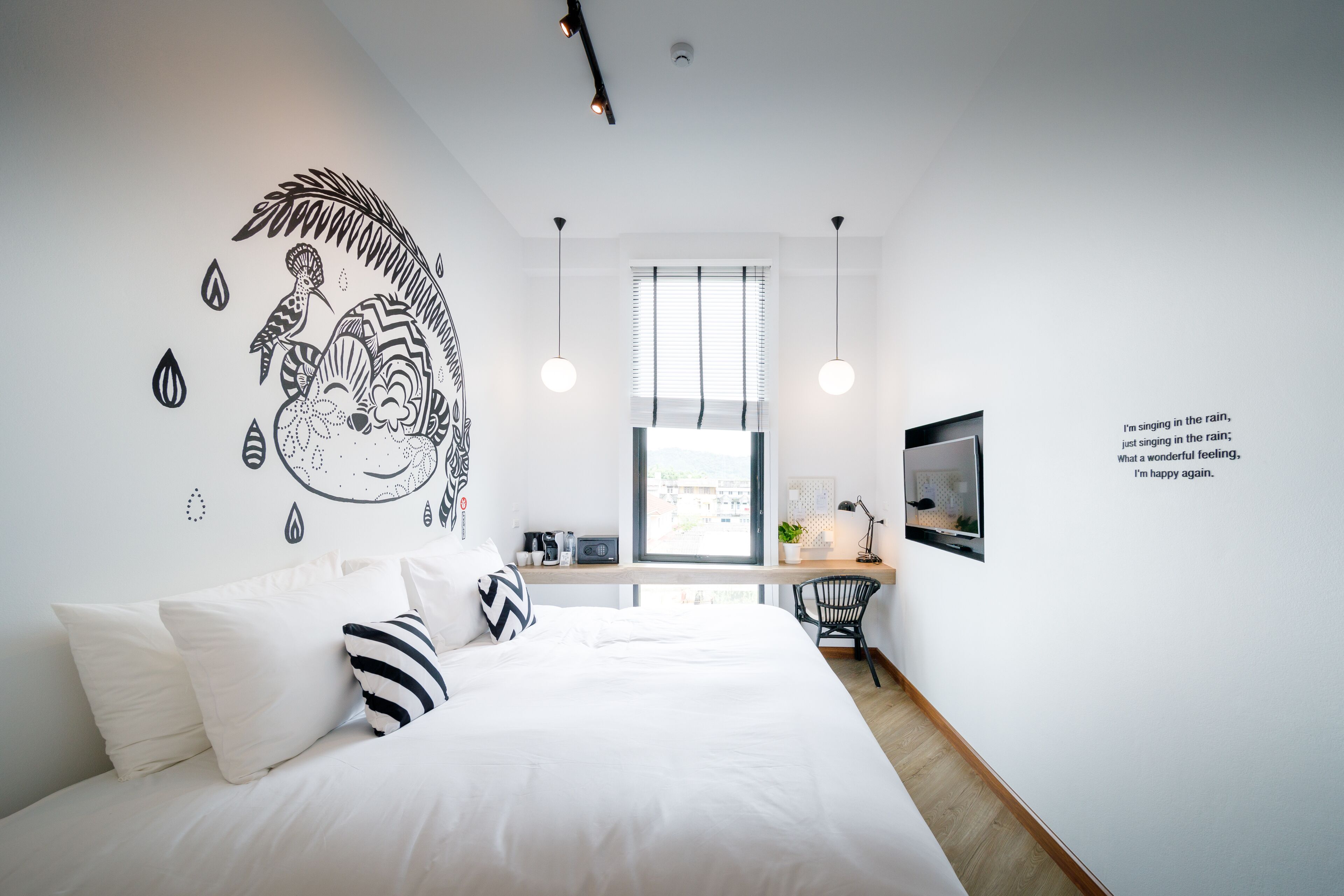 A modern bedroom with a large bed, a desk, and a TV.