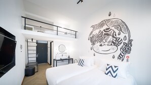 A modern hotel room with a large bed, a small bedside table, a mirror, and a wall mural. There is a staircase leading to an upper level. - Blu Monkey Hub & Hotel Ranong (Ranong)