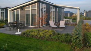Ein modernes Haus mit Terrasse, Sitzgelegenheit im Freien und einem Garten.