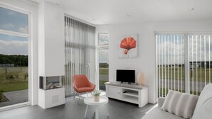 A modern living room with a large window, a flat-screen TV, a red chair, and a grey sofa.