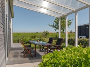 Un patio cubierto con una mesa y sillas, con vistas a un campo verde.
