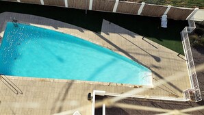 An aerial view of a swimming pool with a tiled deck, a ladder, and a small deck area with a chair. - Apartment in front of La Herradura Beach ideal for the Family (Coquimbo)