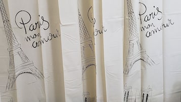 A bathroom with a shower curtain featuring Paris landmarks and the phrase "Paris mon amour".