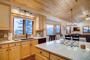 A spacious kitchen with wooden cabinets, granite countertops, and large windows offering views of trees. - Dog Friendly! Epic Views-Spacious TH w/Garage-Quiet Setting & Neighborhood-W/D-Grill-Walk to Trails (Steamboat Springs)