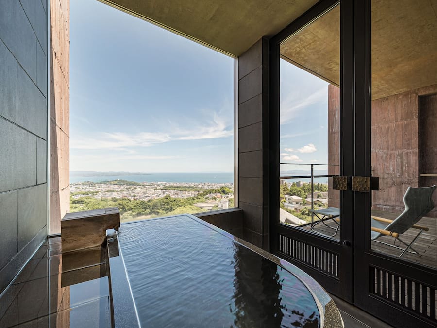 Ein moderner, überdachter Pool mit freiem Blick auf Stadt und Berge im Hintergrund.