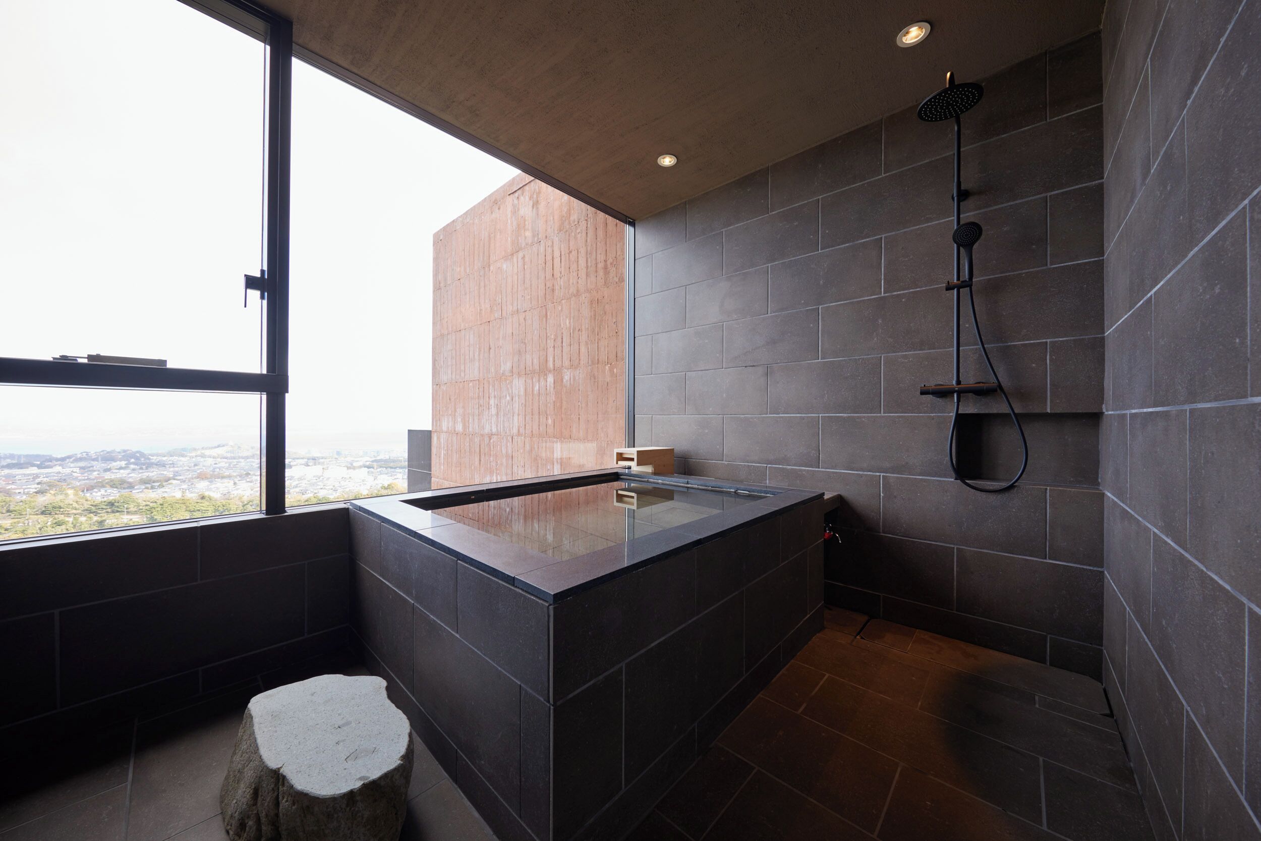 A modern bathroom with a large bathtub, a shower, and a view of the city.