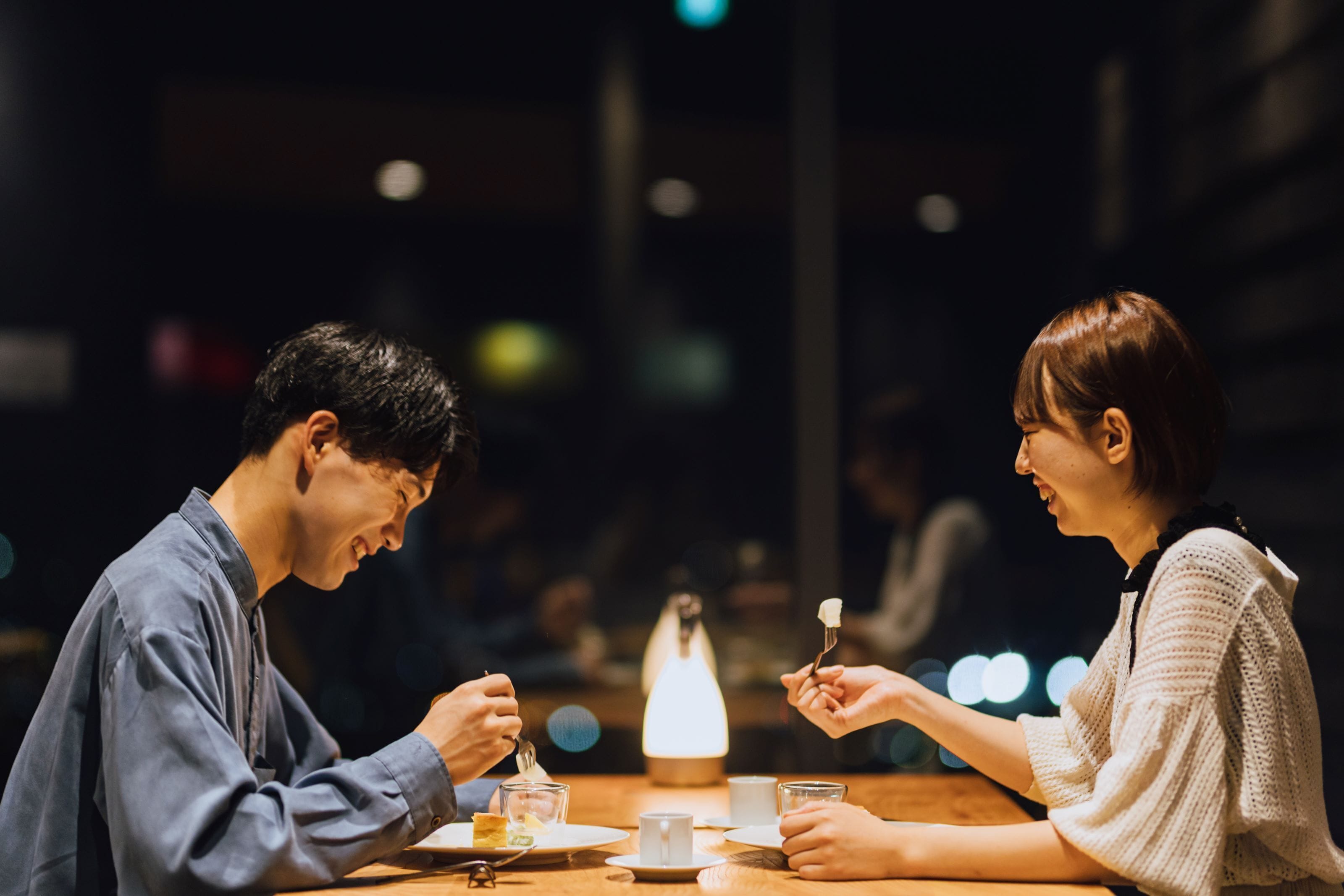 A dimly lit restaurant with a candle centerpiece, wooden tables, and diners.