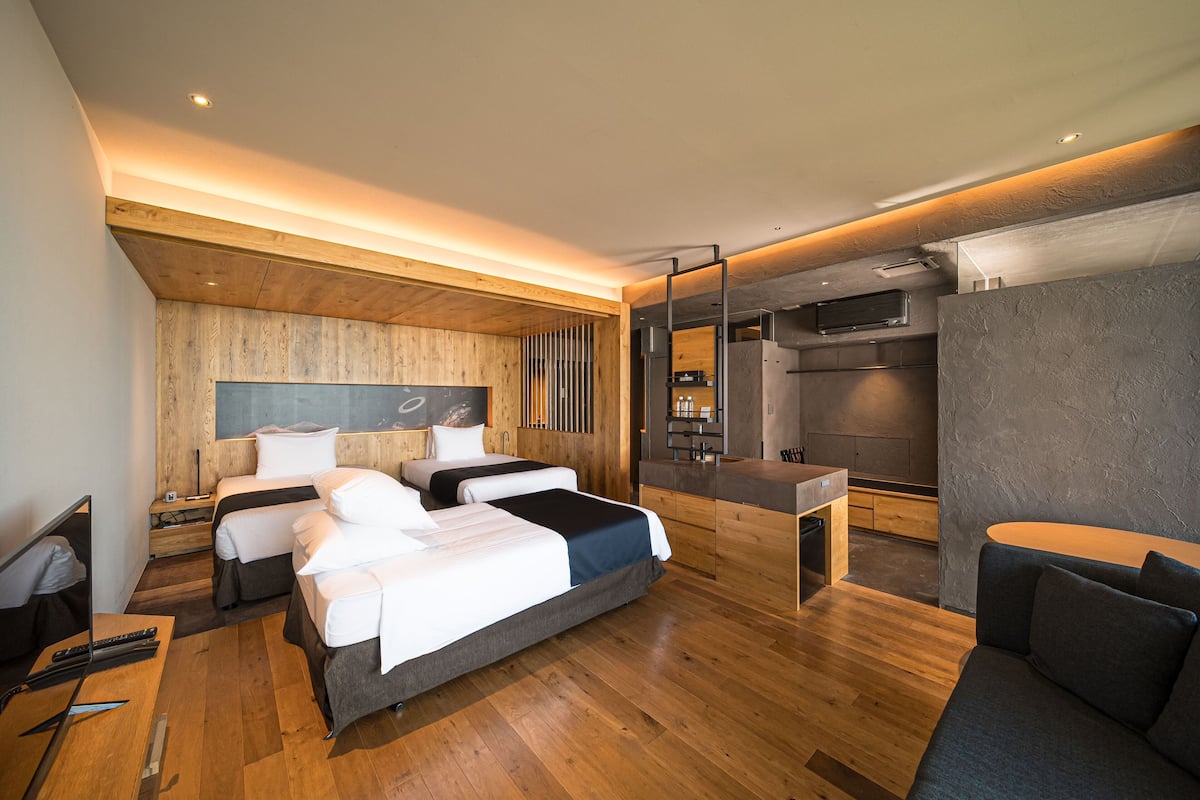 A modern hotel room with a wooden ceiling, a large bed, a desk, and a seating area.