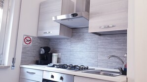 Eine moderne Küche mit Gasherd, Edelstahlspüle und hellen Holzschränken.