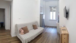 Ein modernes Wohnzimmer mit einem gestreiften Sofa, einem kleinen Holztisch und einem an der Wand befestigten Fernseher.