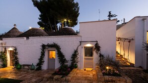 A white building with a tiled roof, a door, and a small staircase leading to an upper level. - Trulli in corte (Alberobello)