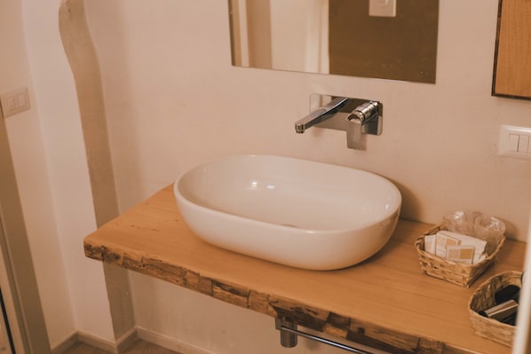 A bathroom with a white sink, wooden countertop, and a mirror above it. - Trulli in corte (Alberobello)