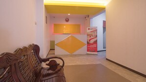A reception area with a reception desk, a digital clock, and a RedDoorz sign. - RedDoorz near ITC Mangga Dua (Jakarta)