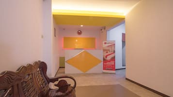 A reception area with a reception desk, a digital clock, and a RedDoorz sign.