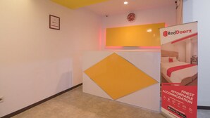 A hotel reception area with a yellow and white color scheme, a clock on the wall, and a RedDoorz sign advertising affordable accommodation. - RedDoorz near ITC Mangga Dua (Jakarta)