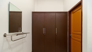 A room with a large wardrobe, a mirror, and a door. - RedDoorz near Kejaksan Station Cirebon 2 (North Cirebon)