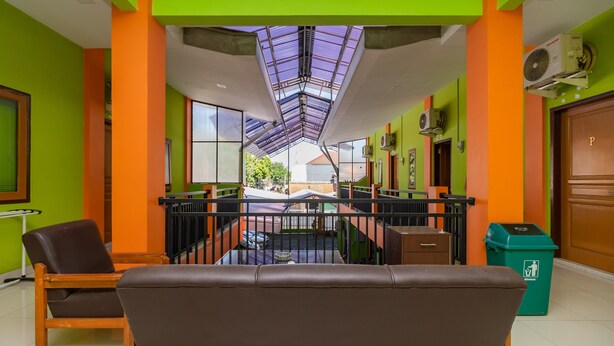 A hotel lobby with a central seating area, a glass ceiling, and a view of the street outside. - RedDoorz near Kejaksan Station Cirebon 2 (North Cirebon)