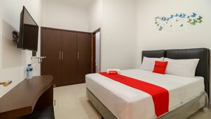 A hotel room with a bed, a desk, a TV, and a wardrobe. - RedDoorz near Kejaksan Station Cirebon 2 (North Cirebon)