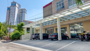 Un bâtiment RedDoorz doté d’un espace de stationnement couvert et où plusieurs voitures sont garées devant.