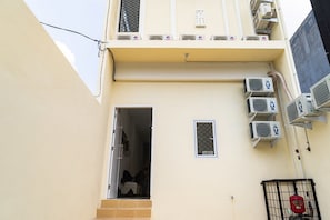 A building with multiple air conditioning units, a small window, and a fire extinguisher.