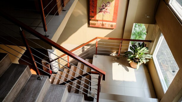 A multi-level interior with a staircase, a painting on the wall, and a potted plant. - RedDoorz near Kebun Raya Bogor 2 (Bogor)