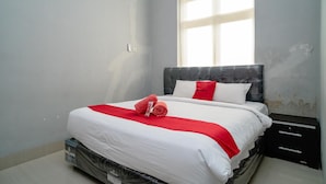 A neatly made bed with white and red bedding, a marble headboard, and a window with blinds. - RedDoorz @ Jalan Pendidikan Mataram (Mataram)