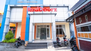A hotel named 'edotel' with a 'RedDoorz' sign, featuring a modern facade with blue and orange accents, and several motorcycles parked in front. - RedDoorz @ Jalan Pendidikan Mataram (Mataram)