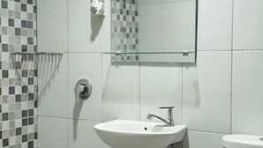 A bathroom with a white sink, a mirror above it, a showerhead, and a toilet. - RedDoorz Hostel @ Manado Green Hostel (Manado)