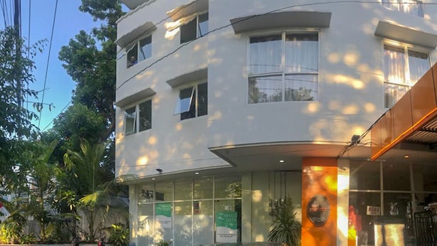 A multi-story hotel with a white facade, large windows, and a visible sign for 'Miranda'. - RedDoorz Hostel @ Manado Green Hostel (Manado)