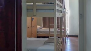A room with bunk beds, a wooden floor, and a door. - RedDoorz Hostel @ Manado Green Hostel (Manado)