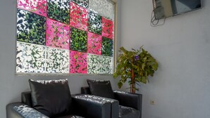 Una sala moderna con un sofá seccional, un ventanal decorativo con un estampado floral y una planta en maceta.