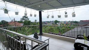Un balcon agrémenté de jardinières suspendues, doté d’une balustrade et offrant une vue sur les environs.