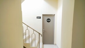 Un escalier avec une rampe métallique menant à une porte portant l’inscription « P-01 » et un panneau indiquant « Zone fumeurs ».