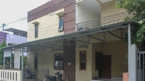 A two-story building with a covered entrance and a motorcycle parked outside. - KoolKost Syariah near Universitas Ahmad Dahlan Kampus 1 (Yogyakarta)