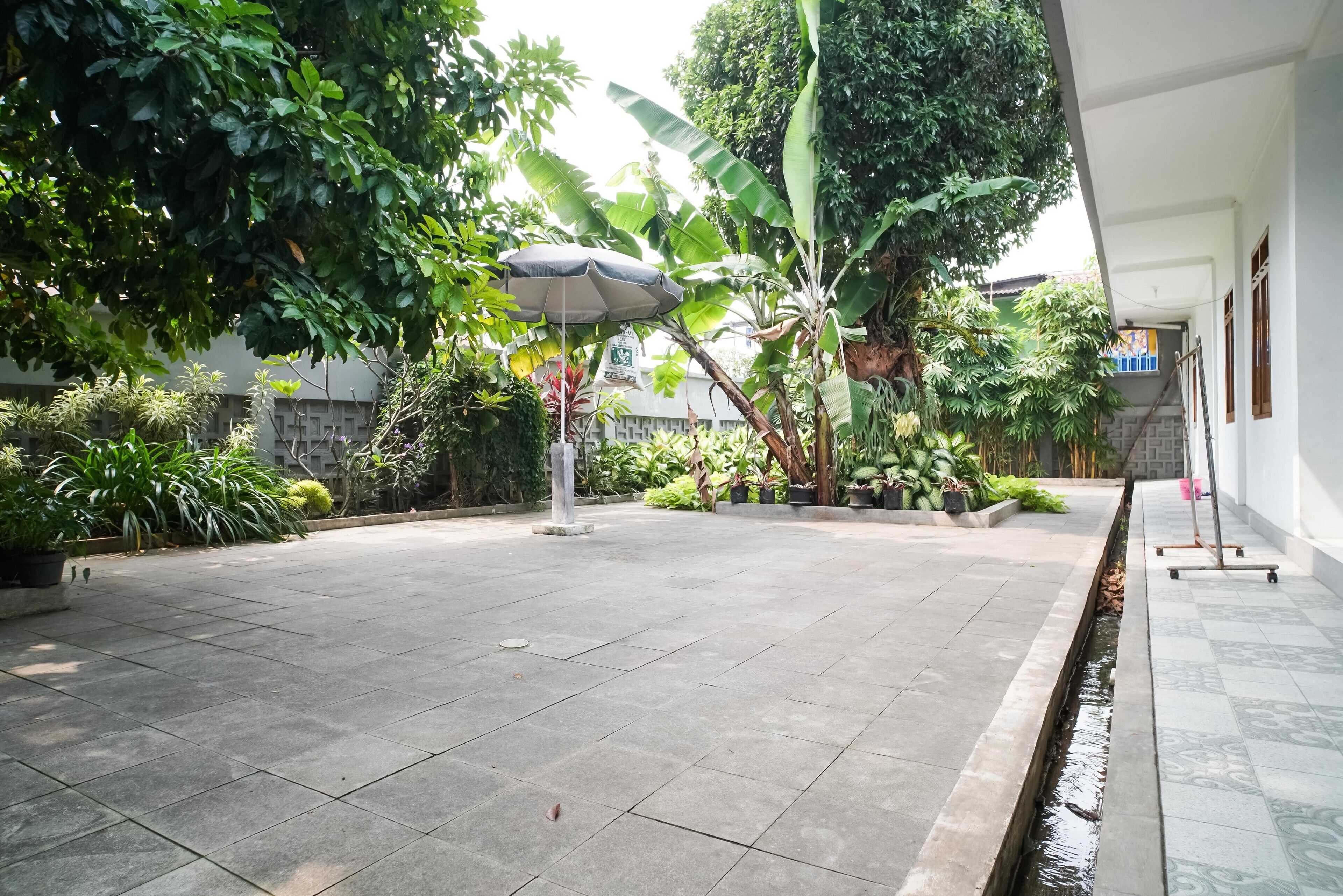 A courtyard with a tiled floor, potted plants, a water feature, and a covered seating area.