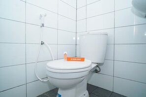 Et hvidt toilet med hvid tank og bidet. Der er en kasse med teksten "KOOL KOST" på tanken.