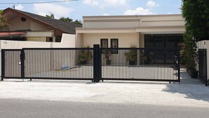 Un lotissement résidentiel fermé, doté d’une allée pavée et d’une maison moderne à toit plat.