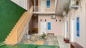 Ein mehrgeschossiges Gebäude mit Treppe, Balkon und einem kleinen Garten mit einer Bank.