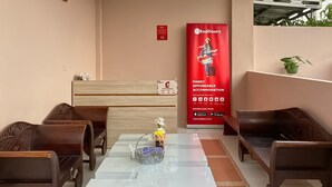 Eine Hotelhalle mit Rezeption, Sitzbereich und einer RedDoorz-Werbeanzeige.