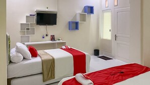 Ein Hotelzimmer mit zwei Betten, einem Fernseher, einem Schreibtisch und einem Fenster mit Jalousien.