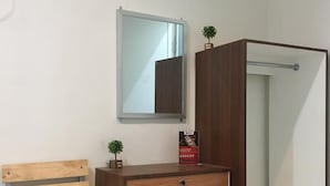 A bathroom with a wooden vanity, a mirror, and a small potted plant. - RedDoorz near Institut Kesehatan Helvetia (Medan)