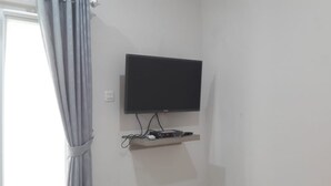 Habitación con una televisión de pantalla plana montada en la pared, un enchufe y un sistema de gestión de cables.