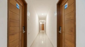 A hallway with wooden doors, each marked with a number. - RedDoorz Plus @ Cemara Asri Medan (Medan)