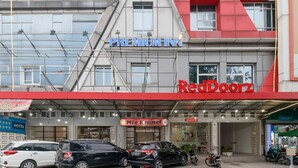 A hotel with a red and grey facade, named "Premium Inn," and a RedDoorz store below. - RedDoorz Plus @ Cemara Asri Medan (Medan)