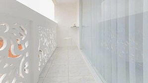 A narrow corridor with a white decorative railing on one side and a glass door on the other. - KoolKost Syariah near Bintaro Jaya Xchange (South Tangerang)