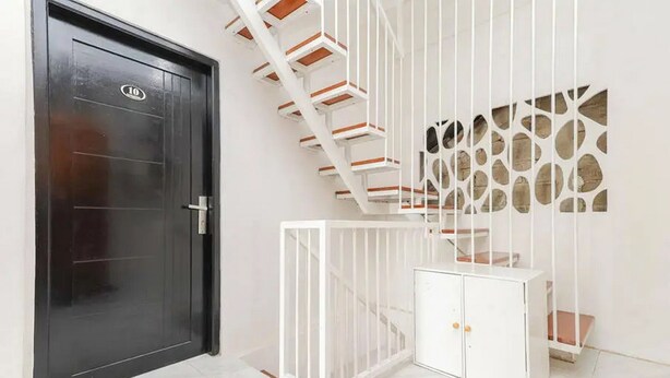 A staircase with white railings and a black door with a number plate. - KoolKost Syariah near Bintaro Jaya Xchange (South Tangerang)