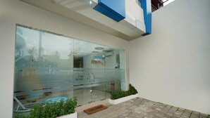 A modern building with a glass facade, a doormat, and a tiled ground.