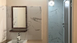 A bathroom with a marble sink, a mirror, and a shower area. - RedDoorz near XT Square 3 (Yogyakarta)